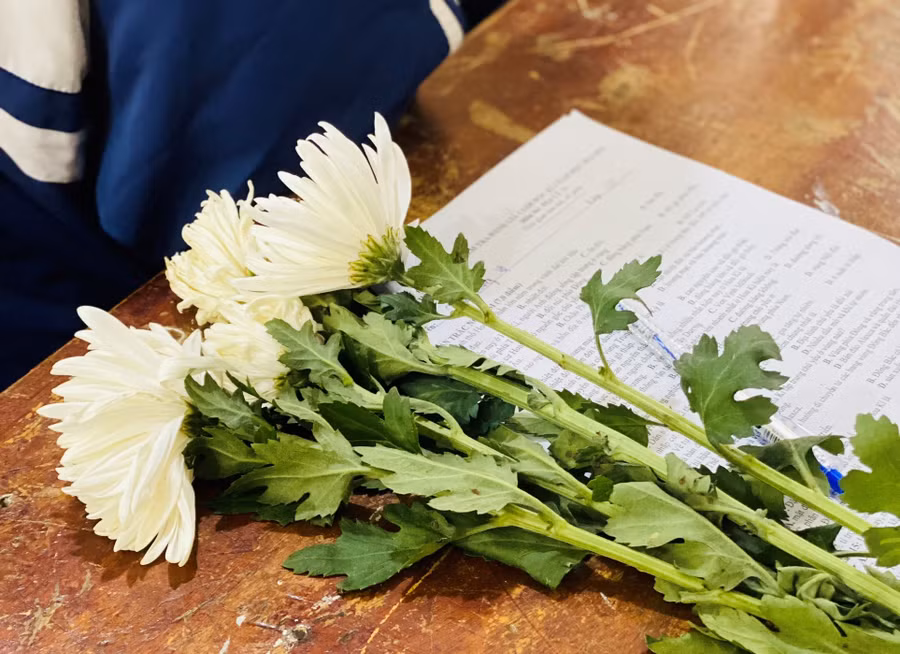 Hình ảnh những bông cúc trắng bên bài kiểm tra cuối kỳ trong lớp 11C (Trường THPT Thành Sen).