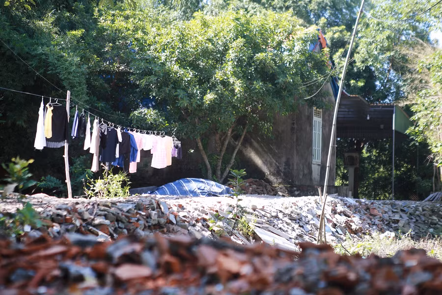 Để tránh ngập lụt, ông Trần Văn Lý (khối Tân Phượng) bỏ tiền mua rác thải xây dựng đắp con đường dài hàng chục mét nối từ nhà ra đường bê tông chính. Ảnh: Phạm Tâm