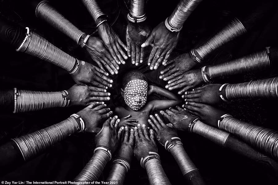 Bức ảnh chụp một cậu bé Suri ở Thung lũng Omo của Ethiopia. Bao quanh là những người phụ nữ địa phương, nổi bật với những chiếc vòng bằng đồng trên tay của tác giả Zay Yar Lin đến từ Myanmar.