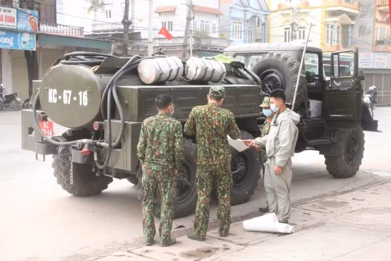 Chiến sĩ Phòng Hóa học khẩn trương vận chuyển hóa chất (dạng khô) lên xe chuyên dụng, sau đó thực hiện công đoạn pha thuốc trên xe. Ảnh: Trần Trang