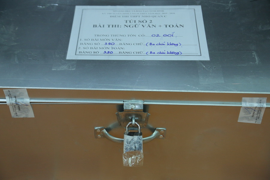 Một thùng đựng bài thi có 3 tem niêm phong cùng nhãn ghi số gói bài thi, môn thi, số lượng bài thi, chuẩn bị cho hoạt động của Ban làm phách, Ban chấm thi Một thùng đựng bài thi có 3 tem niêm phong cùng nhãn ghi số gói bài thi, môn thi, số lượng bài thi, chuẩn bị cho hoạt động của Ban làm phách, Ban chấm thi