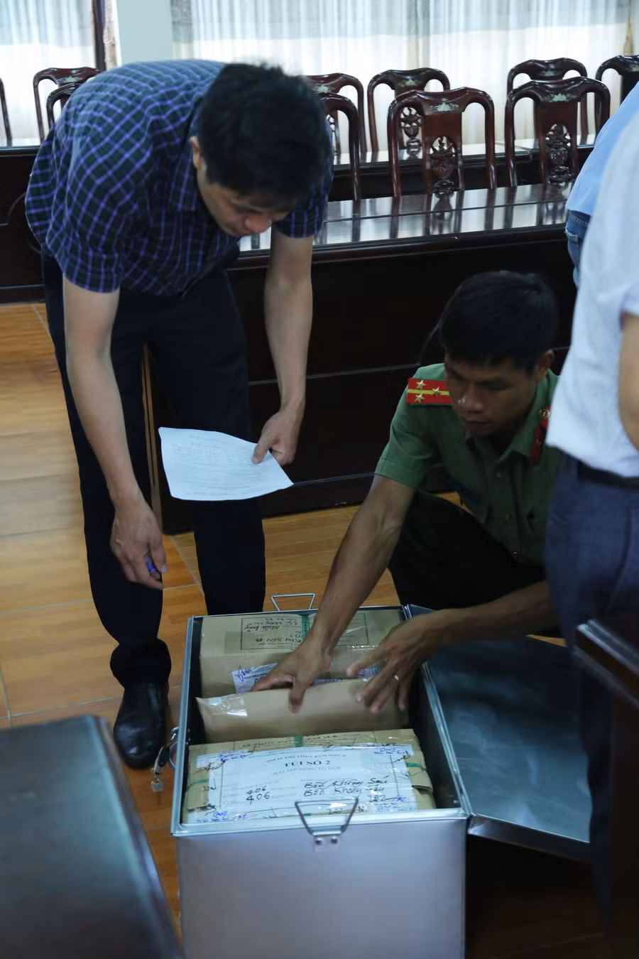 Thư ký Hội đồng thi và công an đang kiểm đếm các túi đựng bài thi trong thùng đựng bài thi của Điểm thi THPT Kim Sơn B