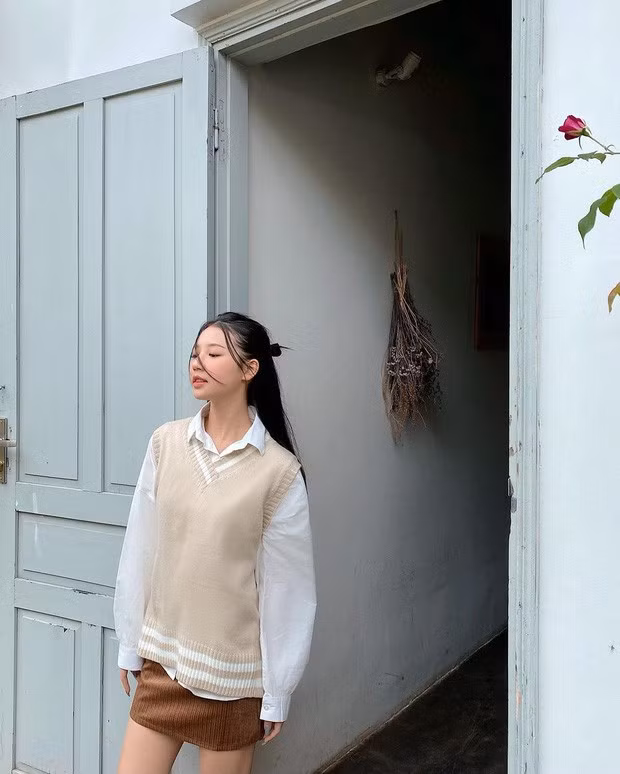 Amee chọn cách mix áo len ba lỗ với áo sơ mi trắng cùng chiếc váy nâu be làm điểm nhấn, mang phong cách vừa dịu dàng lại vừa năng động.