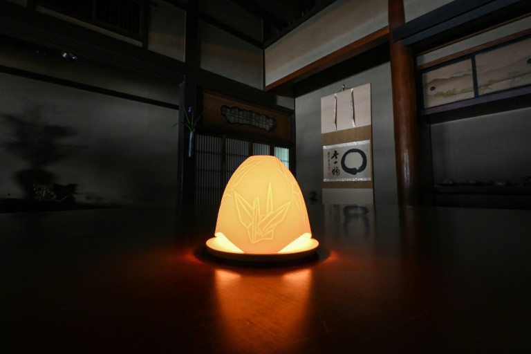 Một giá đỡ nến bằng gốm được tráng men bằng tro từ những con hạc giấy trong xưởng Taigendo. Ảnh: AFP - Richard A.Brooks Một giá đỡ nến bằng gốm được tráng men bằng tro từ những con hạc giấy trong xưởng Taigendo. Ảnh: AFP - Richard A.Brooks