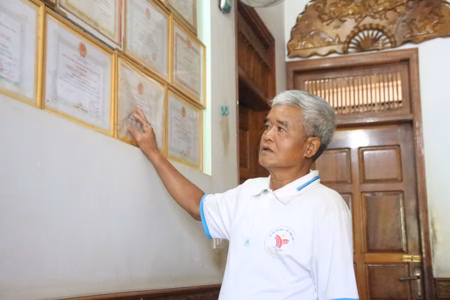 Ông Xiêng Var Nùng tỉ mẩn lau chùi hàng chục tấm Giấy khen, Bằng khen mà bản thân và gia đình vinh dự nhận được.