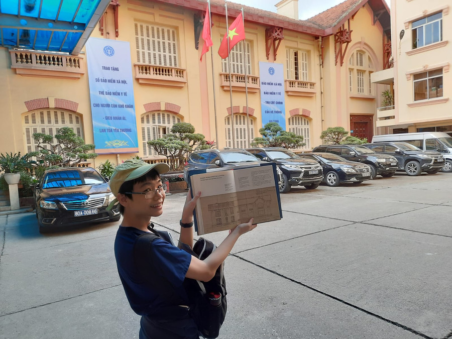 Tuấn Bình thích thú so sánh một di sản kiến trúc thực tế và trong sách 'Kiến trúc Pháp - Đông Dương, những viên ngọc quý tại Hà Nội'. Ảnh: Bruno Depale Tuấn Bình thích thú so sánh một di sản kiến trúc thực tế và trong sách 'Kiến trúc Pháp - Đông Dương, những viên ngọc quý tại Hà Nội'. Ảnh: Bruno Depale