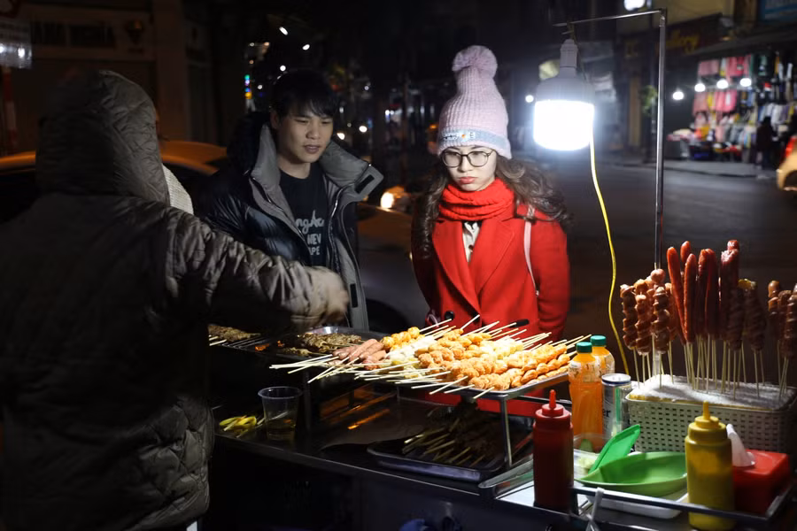 Các hàng đồ nướng cũng hút khách, có nhiều khách nước ngoài cũng tỏ ra rất thích thú khi thưởng thức đồ nướng của Hà Nội trong cái lạnh đầu Đông.