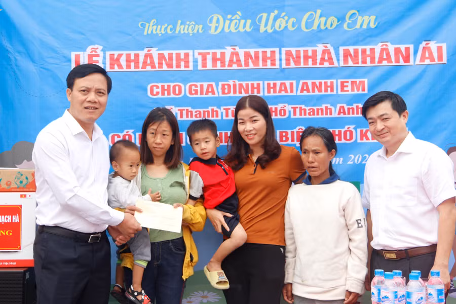 Ông Nguyễn Văn Khoa - Chủ tịch UBND huyện Thạch Hà (bên trái) trao quà của huyện đến gia đình chị Thương trong Lễ bàn giao nhà nhân ái.