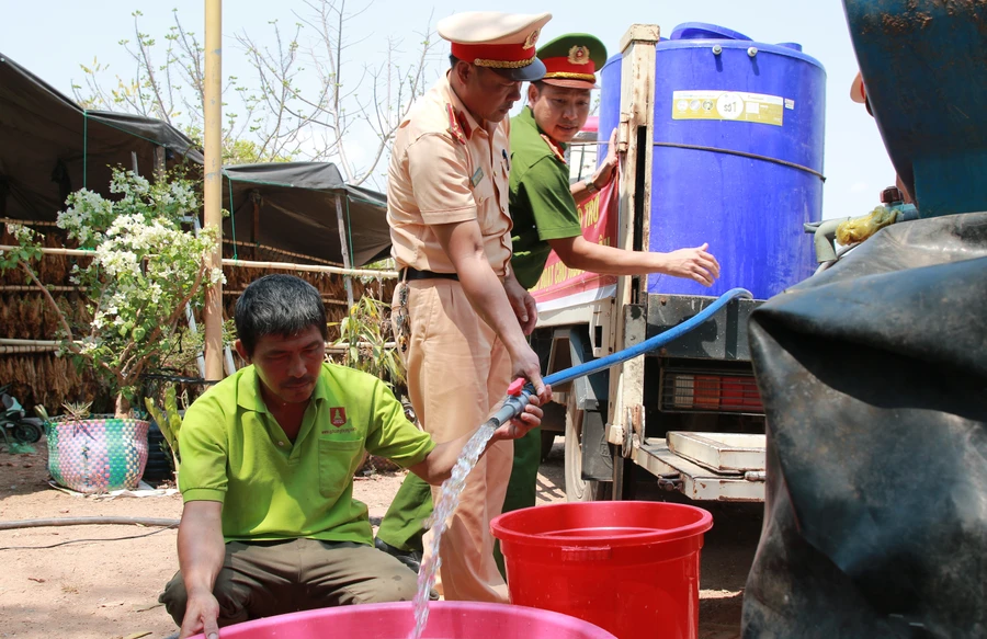 Lực lượng Công an Ea Súp tiếp nước cho hộ ông Lò Văn Kiều. (Ảnh: Thành Tâm)