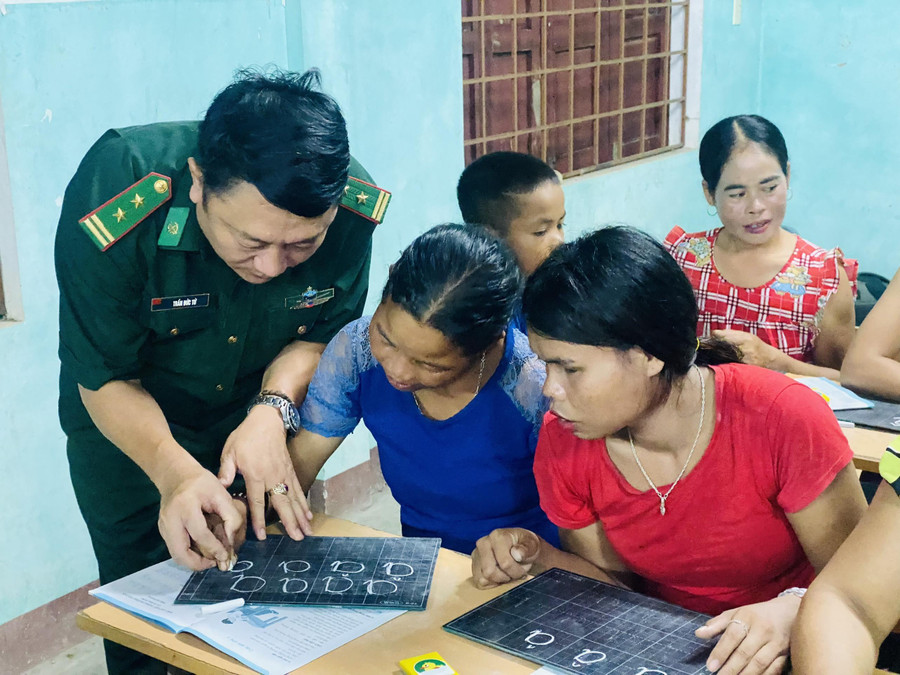 Trung tá Trần Đức Tứ - Chính trị viên Đồn Biên phòng Ba Tầng hướng dẫn các chị phụ nữ tập viết. Ảnh: Văn Hữu