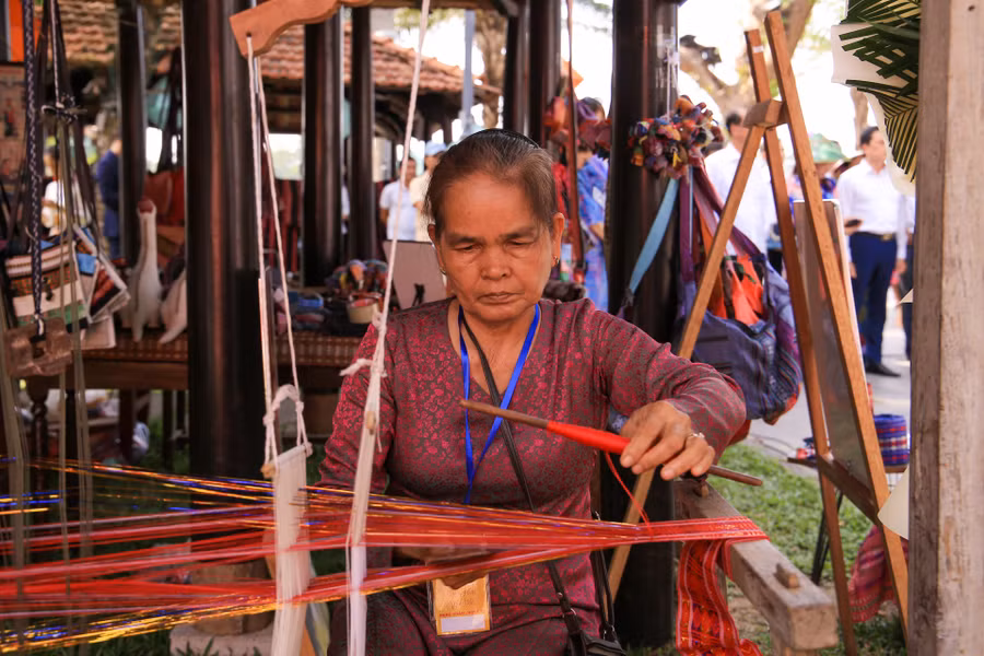 Nghệ nhân đang dệt vải thuộc Làng dệt thổ cẩm Chăm mỹ nghiệp tại không gian trưng bày.