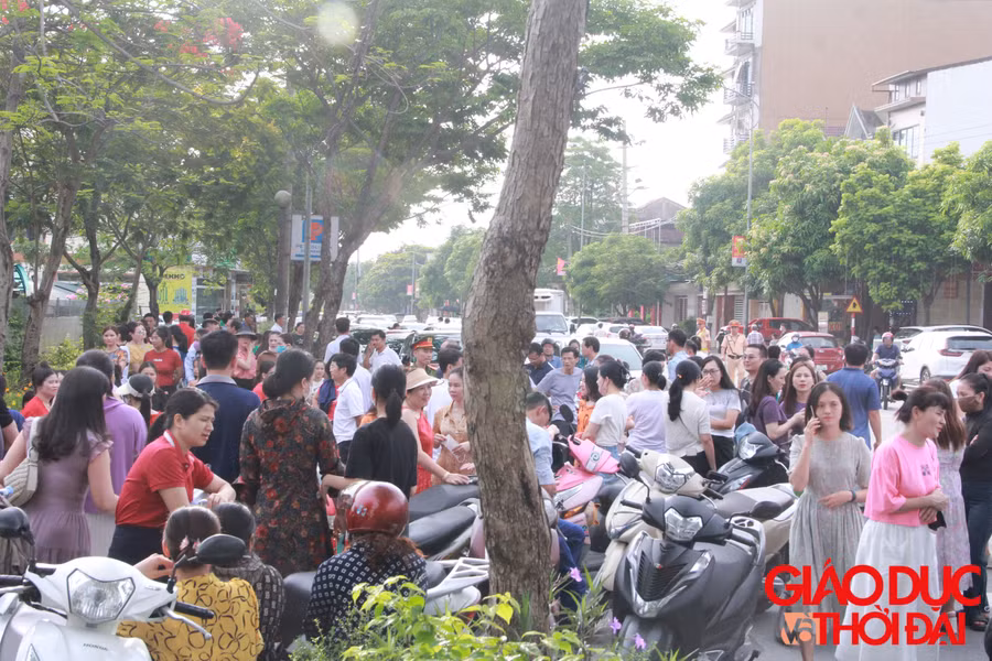 Bên ngoài phòng thi, sức "nóng" không hề kém cạnh khi rất nhiều phụ huynh hồi hộp theo dõi con mình làm bài. (Ảnh: Vũ Long)