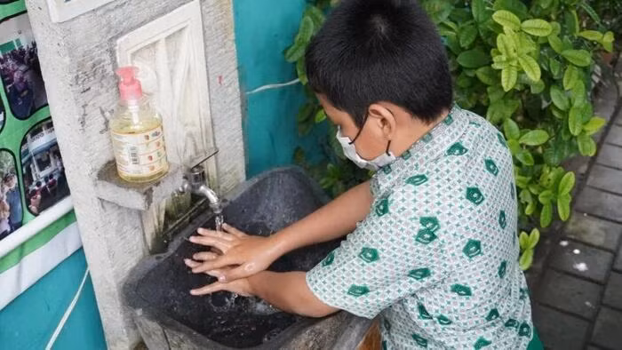 Một học sinh Indonesia rửa tay trước khi vào giờ học.