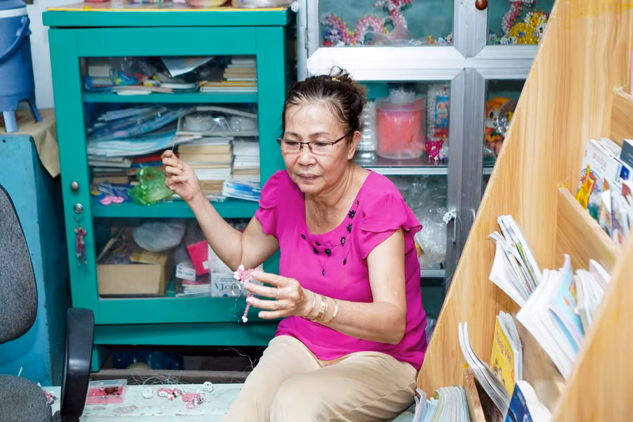 Cô Hiếu kết hạt cườm làm móc khóa tại một góc của lớp học.