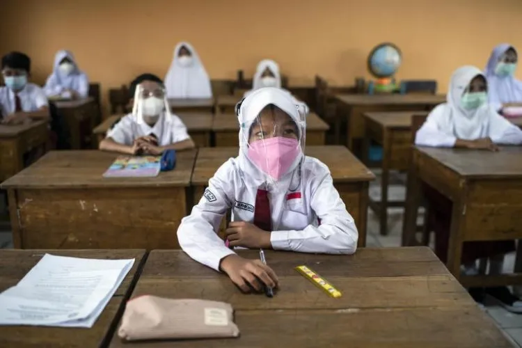 Học sinh Indonesia đeo kính chắn giọt bắn trong lớp học.