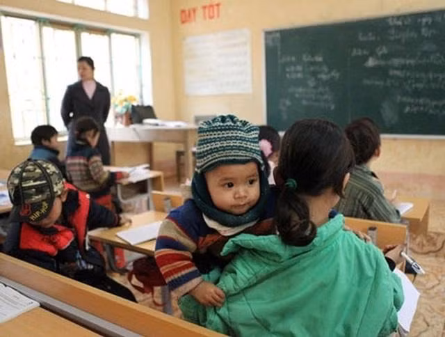 Vừa ngồi trong lớp học bài, Mũ vừa phải bế em. Ảnh: Trọng Trinh, Tuấn Hợp.