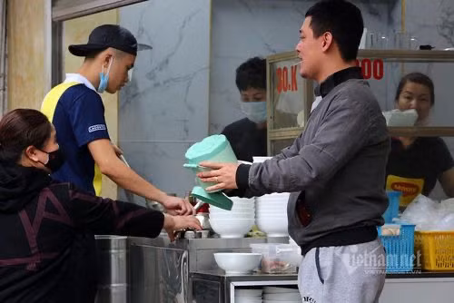 Rất đông khách đến mua phở gà mang về, người bán và phục vụ quán không đeo khẩu trang. Ảnh: VNN.