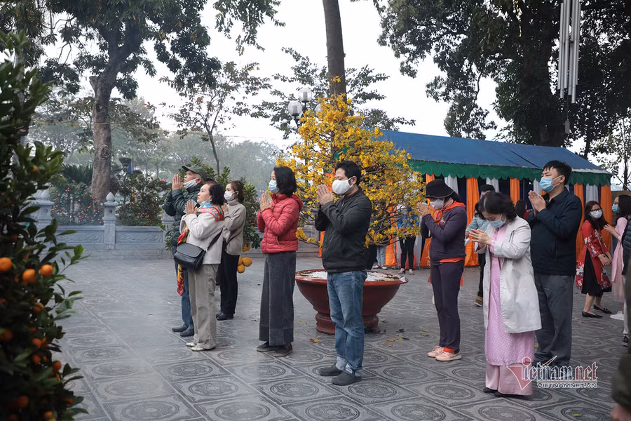 Ghi nhận tại chùa Trấn Quốc sáng mùng 1 Tết, phần lớn người dân chấp hành nghiêm chỉnh việc đeo khẩu trang, một số người khi lễ bỏ khẩu trang xuống. Ảnh: VNN.