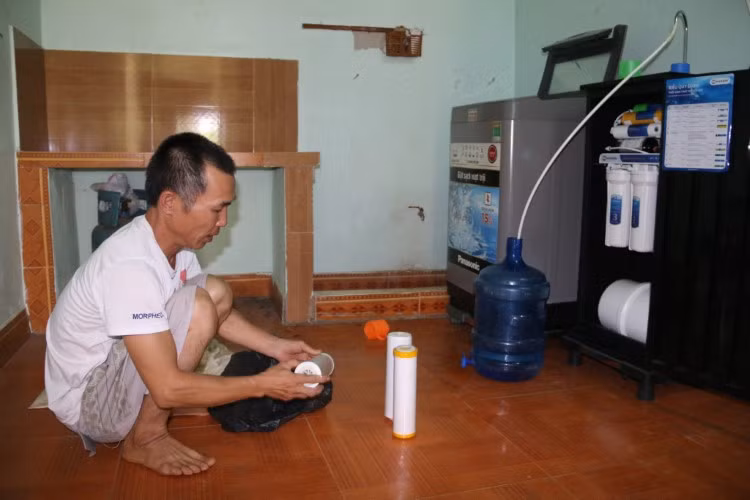 Ông Đinh Mạnh Hùng thay lõi lọc của bình nước ở gia đình.