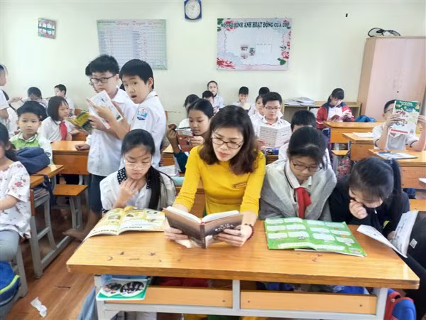 Cô giáo Hệ Ngân quây quần đọc sách cùng học trò. Ảnh: NH.