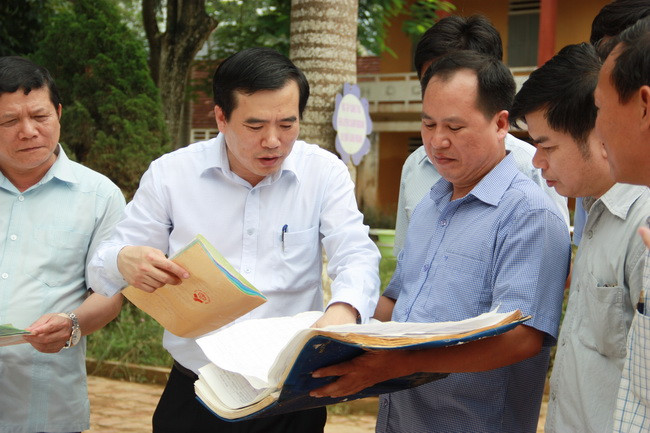 Ông Nguyễn Minh Tường cùng các cán bộ xem xét hồ sơ, sổ sách bị hỏng do ngập nước. 
