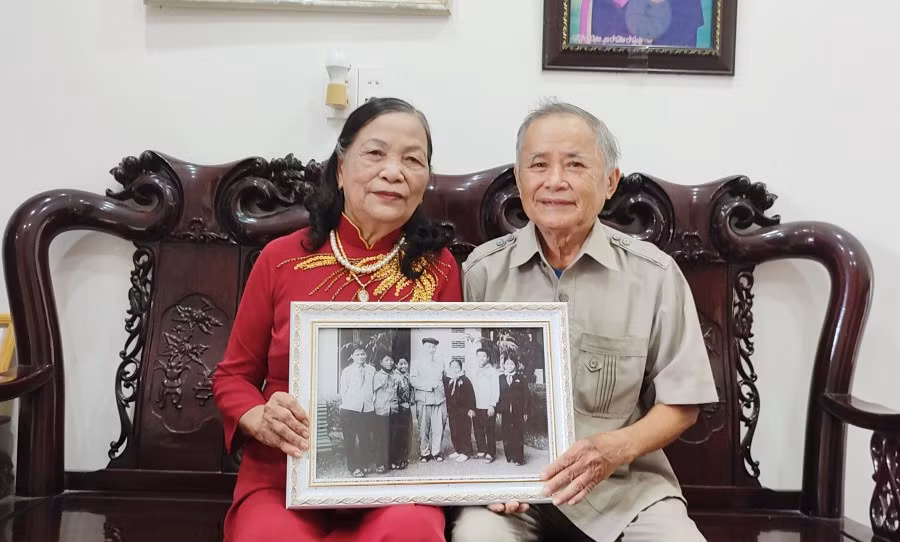 Vợ chồng ông Thỉ bên bức ảnh ông Thỉ cùng các bạn thiếu nhi chụp hình kỷ niệm với Bác Hồ.