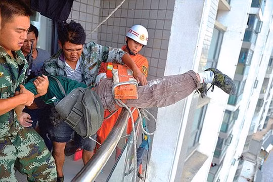 Rescued: Firemen and police officers hauled the construction worker through an 11th floor window on Monday