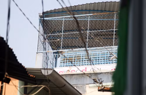 Tầng sân thượng mà nghi can được cho là treo lên lưới sắt và nhảy qua nóc nhà bên cạnh. Tấm bạt còn dính máu. Ảnh: An Nhơn