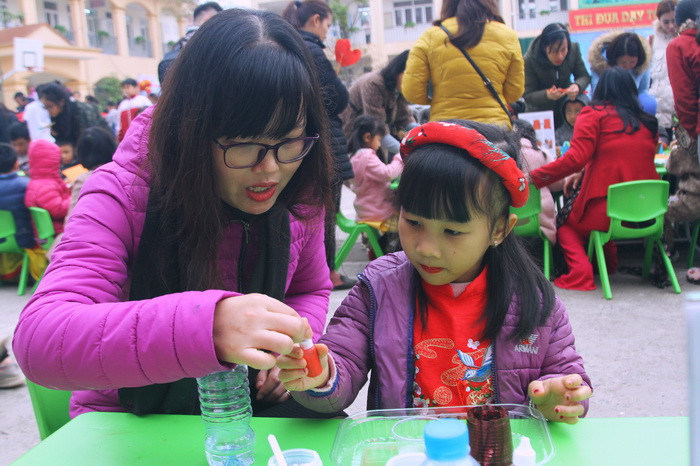 Cô giáo đang hướng dẫn trẻ với các lọ phẩm màu mô phỏng hiện tượng núi lửa phun trào