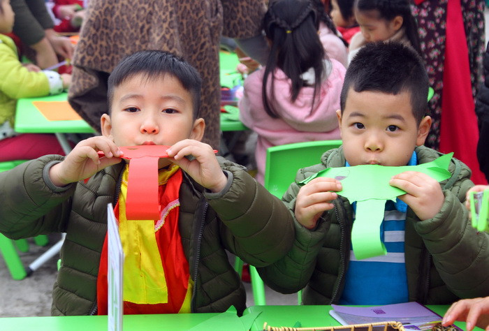Hai trẻ này đang cùng nhau thi thổi voi giấy sau khi hoàn thành làm chú voi bằng giấy.