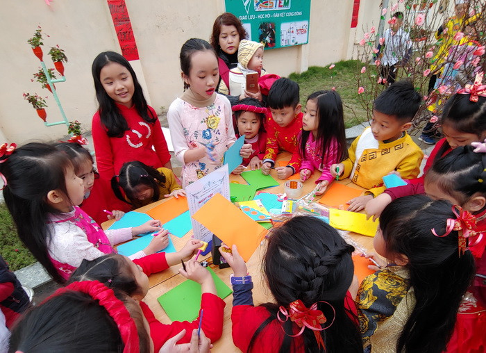 Học sinh Tiểu học đang hướng dẫn các trẻ mầm non cắt dán thủ công, một hoạt động nghệ thuật trong trường mầm non.