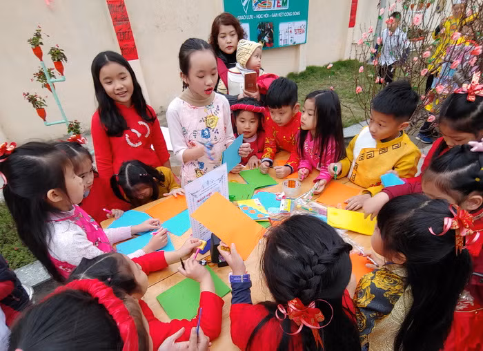 Học sinh Tiểu học đang hướng dẫn các trẻ mầm non cắt dán thủ công, một hoạt động nghệ thuật trong trường mầm non.