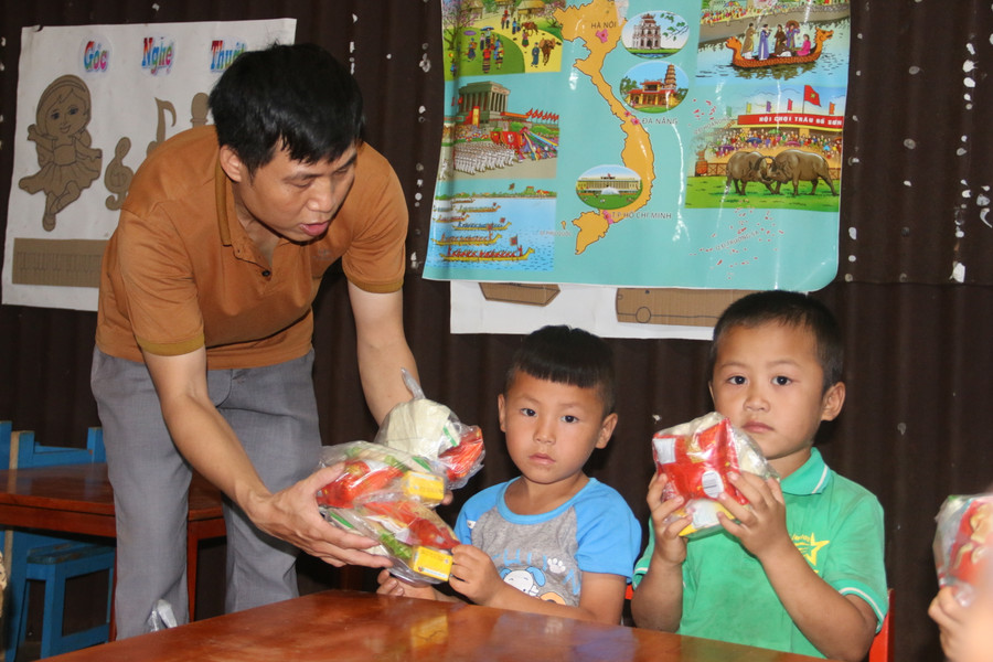 Thầy Hải ân cần đưa túi bánh, kẹo cho học sinh của mình.