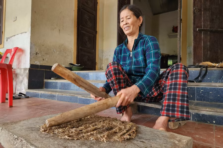 Bà Trương Thị Hải giã cây niệt để làm bột giấy dó. Bà Trương Thị Hải giã cây niệt để làm bột giấy dó.