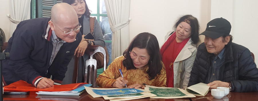 Họa sĩ, nhà nghiên cứu Nguyễn Vi Thủy (giữa) ký tặng tranh của mình tại buổi tọa đàm. Ảnh: Bình Thanh