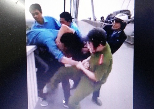 Thượng úy Lê Văn Trình (áo đen) cùng thượng sĩ Hoàng và 2 nhân viên bảo vệ cầu Bính hợp sức kéo nam thanh niên có ý định nhảy cầu tự tử vào phía trong lan can. Ảnh cắt từ clip. hai-cong-an-cuu-nguoi-dinh-tu-tu-vi-thua-ca-do