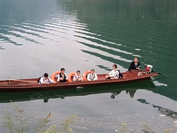 Cô Quách Thị Bích Nụ hàng ngày đưa đón các em qua sông đi học. Ảnh: TG