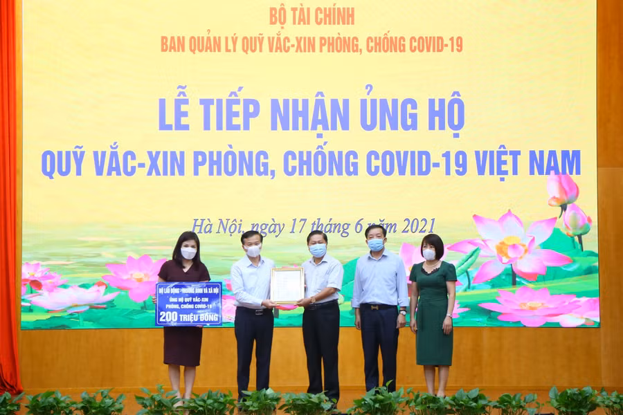 Ông Nguyễn Quang Vinh, Giám đốc Ban Quản lý Quỹ vắc-xin phòng, chống COVID-19 (bên trái) trao Giấy chứng nhận Bộ LĐ-TBXH ủng hội Quỹ vắc-xin cho Thứ trưởng Bộ LĐ-TBXH Lê Tấn Dũng (bên phải). Ảnh: molisa.gov.vn