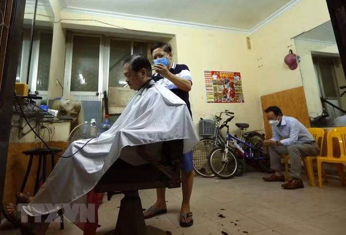 Sáng 22/6, rất đông khách đổ về các cửa hàng cắt tóc, gội đầu khiến khiến nhiều salon phải hoạt động hết công suất, có nơi thậm chí từ chối nhận khách trong buổi sáng do đã kín lịch. Ảnh: TTXVN