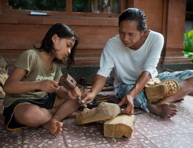 Dưới sự hướng dẫn cẩn thận của ông Anom Suryawan, cậu bé Gusabi có thể là thế hệ thứ 10 trong gia đình họ trở thành một nghệ nhân làm mặt nạ. Ảnh: Rio Helmi Dưới sự hướng dẫn cẩn thận của ông Anom Suryawan, cậu bé Gusabi có thể là thế hệ thứ 10 trong gia đình họ trở thành một nghệ nhân làm mặt nạ. Ảnh: Rio Helmi