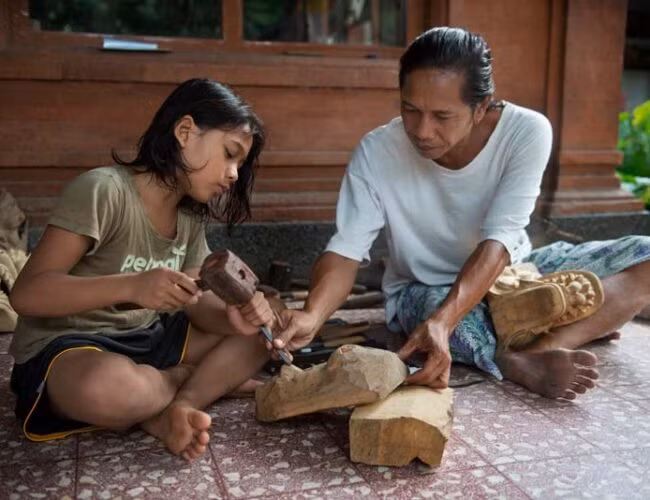 Dưới sự hướng dẫn cẩn thận của ông Anom Suryawan, cậu bé Gusabi có thể là thế hệ thứ 10 trong gia đình họ trở thành một nghệ nhân làm mặt nạ. Ảnh: Rio Helmi