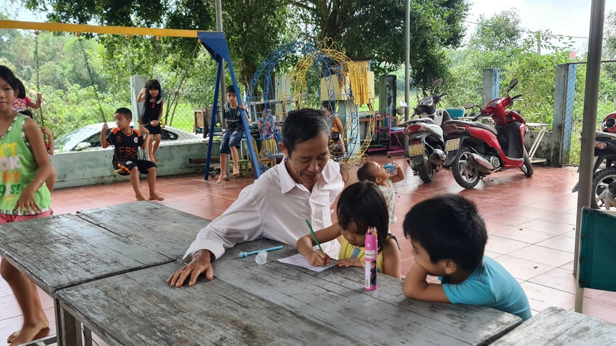 Ông Hùng hướng dẫn các em tập tô màu. Ông Hùng hướng dẫn các em tập tô màu.