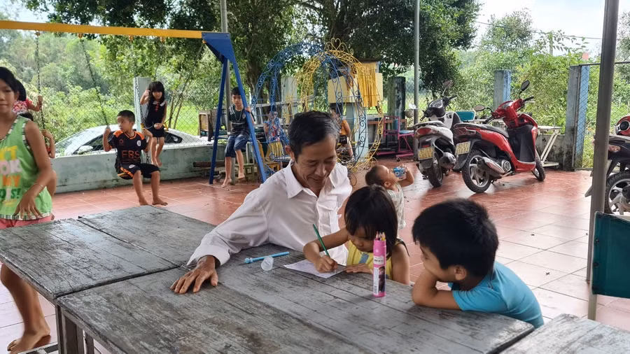 Ông Hùng hướng dẫn các em tập tô màu.