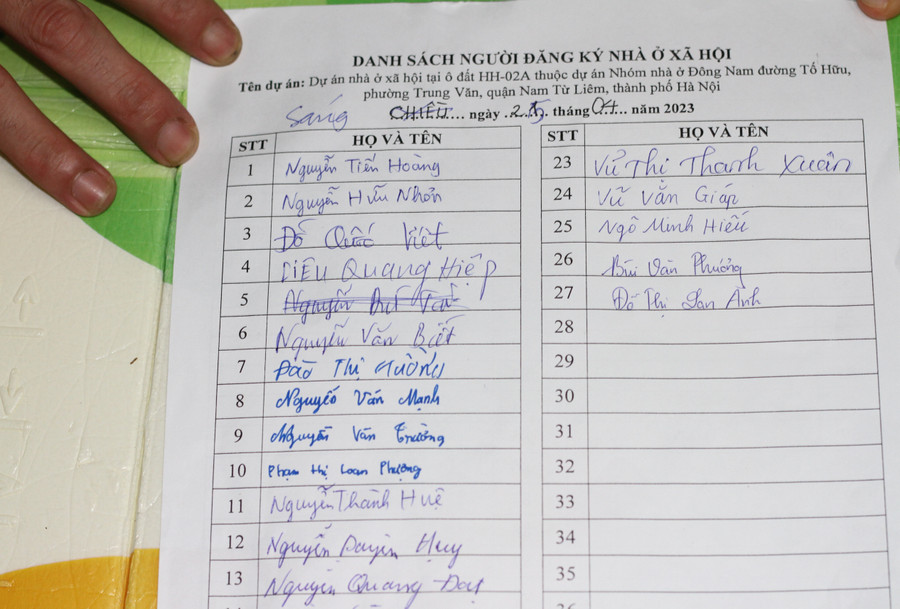 Những người xếp hàng điểm danh vào một tờ giấy do bảo vệ công ty cung cấp.