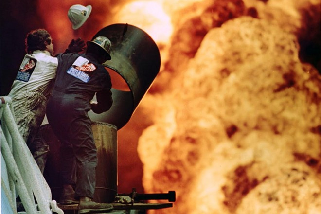 Lính cứu hỏa nỗ lực cắt một phần đường ống và khống chế đám cháy tại giếng dầu ở Kuwait năm 1991. Bức ảnh của phóng viên Russell Boyce cho thấy cảnh đám lửa cháy rực và vụ nổ đã thổi bay mũ bảo hiểm của một lính cứu hỏa. Lính cứu hỏa nỗ lực cắt một phần đường ống và khống chế đám cháy tại giếng dầu ở Kuwait năm 1991. Bức ảnh của nhiếp ảnh gia Russell Boyce cho thấy cảnh đám lửa cháy rực và vụ nổ đã thổi bay mũ bảo hiểm của một lính cứu hỏa.