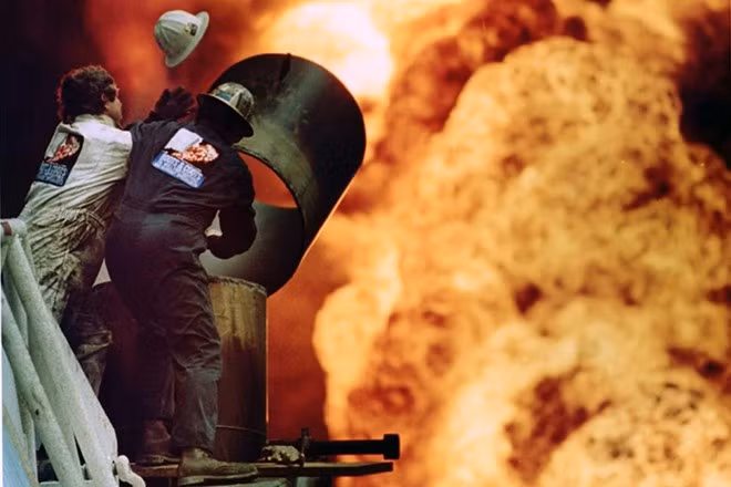 Lính cứu hỏa nỗ lực cắt một phần đường ống và khống chế đám cháy tại giếng dầu ở Kuwait năm 1991. Bức ảnh của nhiếp ảnh gia Russell Boyce cho thấy cảnh đám lửa cháy rực và vụ nổ đã thổi bay mũ bảo hiểm của một lính cứu hỏa. 