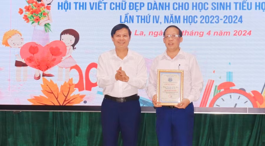 Ông Lê Tiến Quân, Phó giám đốc Sở GD&amp;ĐT (bên trái) trao giải nhất toàn đoàn và giải nhất triển lãm vở sạch - chữ đẹp cho phòng GD&amp;ĐT thành phố Sơn La.