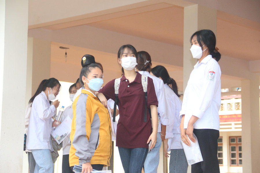 Em Cà Thị Thu Hằng mặc áo vàng tẳng cẩu, đang trao đổi với các thí sinh khác cùng phòng thi.