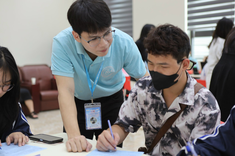 Tình nguyện viên hướng dẫn người tham gia hiến máu viết phiếu đăng ký (ảnh: Quỳnh Anh).