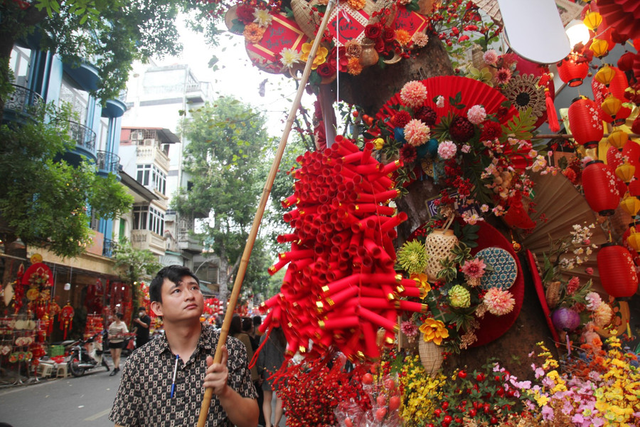 Phố Hàng Mã như được khoác một lớp áo mới, trở nên ấm cúng và ngập tràn sắc màu rực rỡ với các mặt hàng phổ biến như: Câu đối Tết, dây pháo, mâm ngũ quả, bánh chưng, dưa hấu…